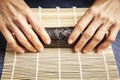 Female chef preparing a roll with rice and nori for a delicious sushi. Asian food concept
