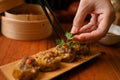 Female chef using chopsticks, garnishing steamed pork or meat dumplings with coriander leaf Royalty Free Stock Photo