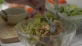 Female chef using spoon and fork mixing all ingredients in a big bowl. Hands of woman preparing spicy chicken salad.