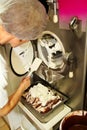 Female chef and worker is working at ice cream factory is cleaning ice cream maker machine from the ice cream leavings. Royalty Free Stock Photo