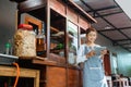 female chicken noodle vendor in apron using a pad