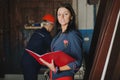 Female chief stands against a worker, during he works at metal c