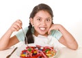 Female child eating dish full of candy in sugar excess and sweet nutrition abuse