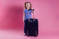 Female child striped blue white t-shirt sitting on a large travel suitcase dream flies rest on the sea shore pink