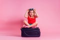 Female child striped red t-shirt and blue shorts sitting on a large travel suitcase dream flies rest on the sea shore
