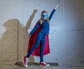 Female child 7 or 8 years old young girl performing happy and excited posing wearing cap and mask in super hero fantasy costume lo Royalty Free Stock Photo