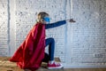 Female child 7 or 8 years old young girl performing happy and excited posing wearing cap and mask in super hero fantasy costume lo Royalty Free Stock Photo