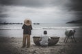 Female with a Chinese weaved hat and a male near a weaved tub near the sea - poverty concept Royalty Free Stock Photo