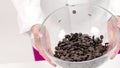 Female chocolatierie shaking chocolate couverture callets in glass bowl slow mo