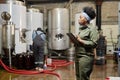 Female Cider Production Worker Using Tablet Computer Inspecting Tanks Indoors Royalty Free Stock Photo