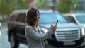 Female city dweller with neck brace is browsing in smartphone on street, walking along road