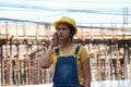 Female civil engineer or architect with yellow helmet, standing and calling with mobile phone Royalty Free Stock Photo