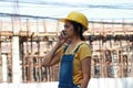 Female civil engineer or architect with yellow helmet, standing and calling with mobile phone Royalty Free Stock Photo
