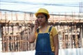 Female civil engineer or architect with yellow helmet, standing and calling with mobile phone Royalty Free Stock Photo
