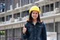 Female civil engineer or architect with yellow helmet, standing and thumbs up