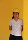 Female civil engineer with yellow helmet and wear white T-shirt. Standing and leaning against the pole on yellow background