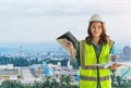 Female Civil engineer with computer blueprint is standing infront Japan industry city in background