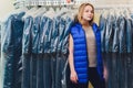 Female cleaner in laundry shop or textile dry-cleaning next to clean clothes in garment bags. Royalty Free Stock Photo