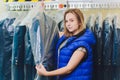 Female cleaner in laundry shop or textile dry-cleaning next to clean clothes in garment bags. Royalty Free Stock Photo