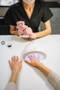 Female client dries gel varnish in the nail dryer