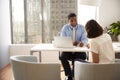 Female Client Signing Document In Meeting With Male Financial Advisor In Office