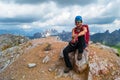 Female climber on Averau peak at the end of a via ferrata route, with dark storm clouds approaching in the background