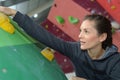 female climber with carbines rope indoor rock-climbing wall