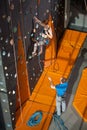 Female climber is climbing up on indoor rock-climbing wall