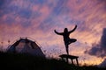 Female climber meditating on bench near tent on mountain slope in Romania