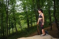 Female climber standing on big natural boulder in the forest