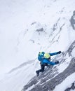 Female climber in the storm during an extreme winter climb.