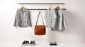 Female clothing on a metal clothes rack. Shirts, shoes, and leather bag on white background. Minimalist wardrobe. Generative AI