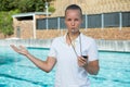 Female coach with stopwatch blowing whistle at poolside