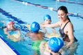 Female Coach In Water Giving Group Of Children Swimming Lesson In Indoor Pool