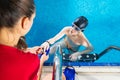 Female Coach In Water Giving preteen boy swimming Lesson In Indoor Pool