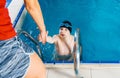 Female Coach In Water Giving preteen boy swimming Lesson In Indoor Pool Royalty Free Stock Photo
