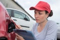 Female coachbuilder inspecting damaged car