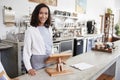 Female coffee shop owner standing smiling behind the counter Royalty Free Stock Photo