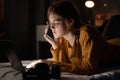 Female college student calling her friends, lying on bed working on laptop at night in dormitory. Royalty Free Stock Photo