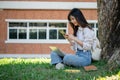A female college student is chatting with her friends while relaxing under the tree in a campus park Royalty Free Stock Photo