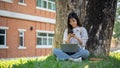 A female college student is chatting with her friends while relaxing under the tree in a campus park Royalty Free Stock Photo