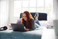 Female College Student Lies On Bed In Shared House Working On Laptop Royalty Free Stock Photo