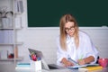 Female college student preparing for test or exam, writing, using computer laptop in classroom. Royalty Free Stock Photo