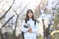 A female college student smiling happily in front of a cherry blossom tree at spring entrance Royalty Free Stock Photo