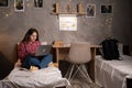 Female college student wearing headphones lying on bed working on laptop in dormitory. Royalty Free Stock Photo