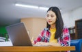 Female college student working on laptop and searching for books to study, make report, find useful information in college room. Royalty Free Stock Photo