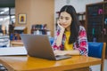 Female college student working on laptop and searching for books to study, make report, find useful information in college room. Royalty Free Stock Photo