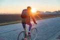 Female commuter riding a bike out of town to a suburban area. Woman cycling along the road at sunset Royalty Free Stock Photo