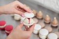 Female confectioner joins the parts of the white macarons with each other using a cream ganache. Close up of pastry chef