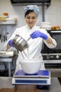 Female confectioner mixing ingredients use blender for preparation sweet pastry cream or dough